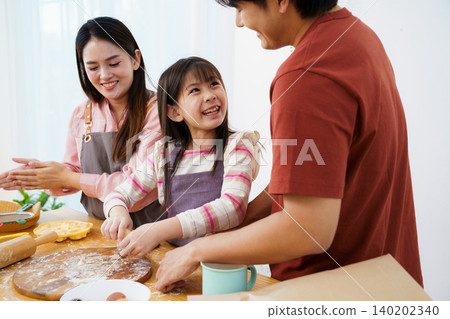 Happy Asian family with little daughter kneading dough in kitchen Happy Asian family with little daughter kneading dough in kitchen 140202340