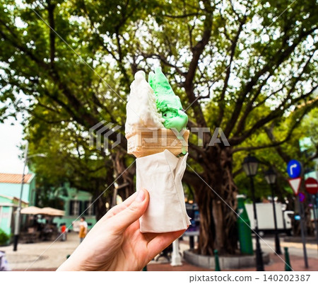 First person view of hand holding traditional Italian gelato ice cream cone with mint and lemon flavors in paper napkin at Taipa Houses in Macau First person view of hand holding traditional Italian gelato ice cream cone with mint and lemon flavors in paper napkin at Taipa Houses in Macau 140202387