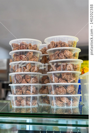 Traditional Chinese Huamei dried preserved plums inside plastic containers stacked on glass shelf inside sweets bakery shop in Macau travel destination 140202388