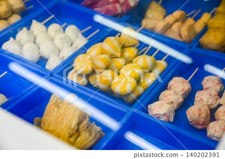 Assorted colorful Chinese fish balls on skewers with striped sea urchin buns inside blue plastic trays at local street food stall in Taipa Macau Assorted colorful Chinese fish balls on skewers with striped sea urchin buns inside blue plastic trays at local street food stall in Taipa Macau 140202391