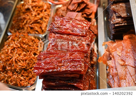 Traditional Chinese Bakkwa sweet pork meat jerky and shredded meat floss inside metal trays at local street food shop display counter in Macau 140202392