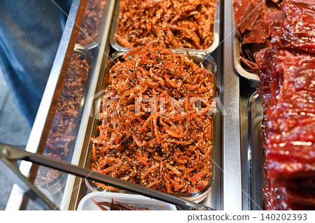 Traditional Chinese shredded sweet pork jerky meat floss with sesame seeds inside glass tray at street food bakery shop display counter in Macau Traditional Chinese shredded sweet pork jerky meat floss with sesame seeds inside glass tray at street food bakery shop display counter in Macau 140202393