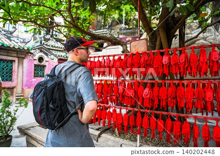 30 years old Russian man tourist on solo travel looking at red wishing plaques on wishing tree in ancient A-Ma Temple in Macau 30 years old Russian man tourist on solo travel looking at red wishing plaques on wishing tree in ancient A-Ma Temple in Macau 140202448