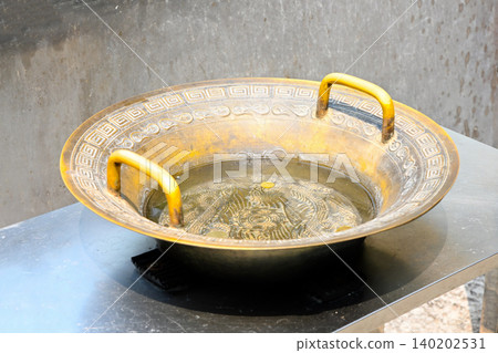 Ancient traditional bronze dragon water basin filled with coins at famous historical A-Ma Temple religious landmark in Macau travel destination China Ancient traditional bronze dragon water basin filled with coins at famous historical A-Ma Temple religious landmark in Macau travel destination China 140202531