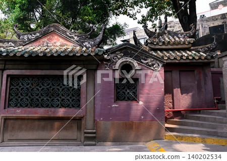 Ancient traditional Chinese architecture with stone wall and tiled roof inside historical A-Ma Temple religious landmark in Macau travel destination 140202534