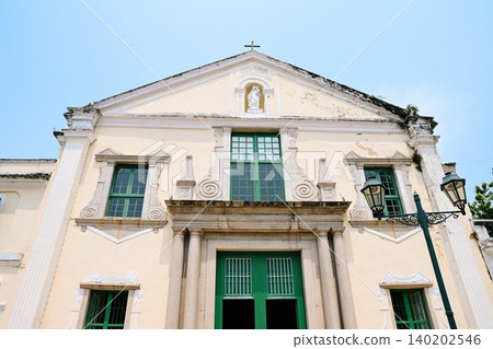 Ancient Portuguese St Augustine Church yellow facade with green window frames and columns during sunny summer day in Macau tourist landmarks China 140202546