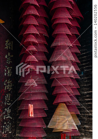 Traditional spiral incense coils hanging with ancient Chinese couplet on pillar meaning eternal paying of respects inside historical Pak Tai Temple Traditional spiral incense coils hanging with ancient Chinese couplet on pillar meaning eternal paying of respects inside historical Pak Tai Temple 140202556