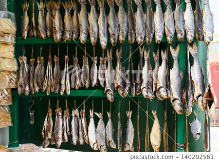 Traditional dried salted fish hanging on green wooden display at local street food market stall in Coloane Macau China Traditional dried salted fish hanging on green wooden display at local street food market stall in Coloane Macau China 140202561