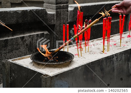 Worshipper hand lighting incense joss stick inside ancient A-Ma Temple built in 1488 in Macau China translation on candles is blessing Worshipper hand lighting incense joss stick inside ancient A-Ma Temple built in 1488 in Macau China translation on candles is blessing 140202565