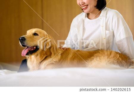 Woman touching dog in bed Woman touching dog in bed 140202615