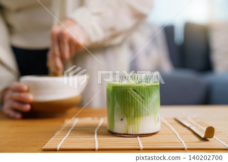 Iced matcha latte in ribbed glass on bamboo mat Iced matcha latte in ribbed glass on bamboo mat 140202700