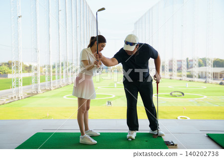 Professional golf coach adjusting posture for female student Professional golf coach adjusting posture for female student 140202738