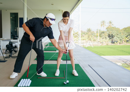 Professional golf coach adjusting posture for female student Professional golf coach adjusting posture for female student 140202742