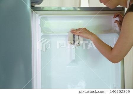 Asian woman cleaning empty refrigerator with cloth Asian woman cleaning empty refrigerator with cloth 140202809