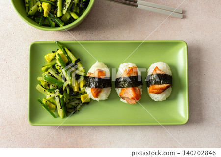Food is arranged on a green plate with salad made of nori, cucumbers, and avocado alongside nagiri sushi topped with red fish, suitable for breakfast or lunch Food is arranged on a green plate with salad made of nori, cucumbers, and avocado alongside nagiri sushi topped with red fish, suitable for breakfast or lunch 140202846
