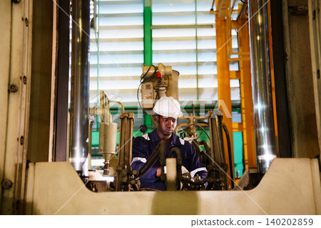 Black engineer using laptop to check machinery in factory Black engineer using laptop to check machinery in factory 140202859