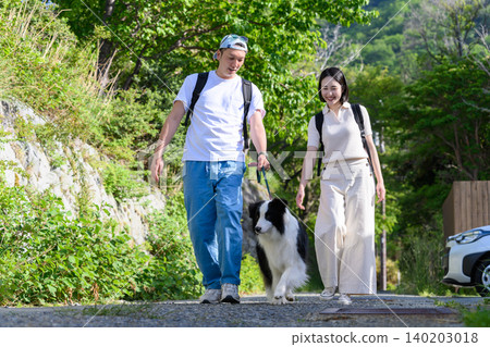 A young couple walking their dog 140203018