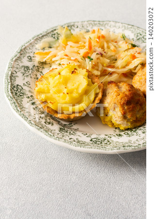Food is arranged on a plate. Baked potato baskets are filled with mashed potatoes. There are turkey meatballs and a serving of fermented cabbage on the side Food is arranged on a plate. Baked potato baskets are filled with mashed potatoes. There are turkey meatballs and a serving of fermented cabbage on the side 140203072