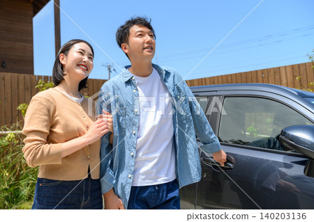 A couple looking at a car and a house A couple looking at a car and a house 140203136