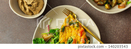 A plate features baked eggs with vegetables alongside a fresh arugula salad. Small bowls hold liver pate and baked pear pieces. This meal is set on a neutral table, banner A plate features baked eggs with vegetables alongside a fresh arugula salad. Small bowls hold liver pate and baked pear pieces. This meal is set on a neutral table, banner 140203543