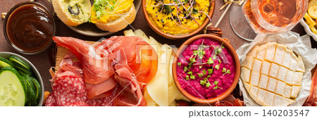 Enjoy a vibrant charcuterie board filled with assorted cheeses, savory sausages, creamy hummus, nuts, and colorful vegetables. Perfect for sharing at a casual gathering, banner Enjoy a vibrant charcuterie board filled with assorted cheeses, savory sausages, creamy hummus, nuts, and colorful vegetables. Perfect for sharing at a casual gathering, banner 140203547