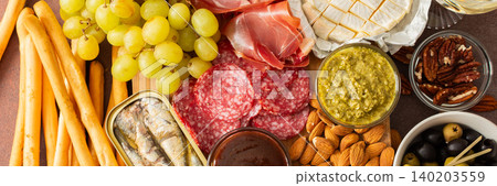 A vibrant charcuterie board showcases a variety of cheese, sausages, hummus, nuts, and sandwiches. Friends gather at a sunny outdoor picnic, enjoying delicious food together, banner A vibrant charcuterie board showcases a variety of cheese, sausages, hummus, nuts, and sandwiches. Friends gather at a sunny outdoor picnic, enjoying delicious food together, banner 140203559