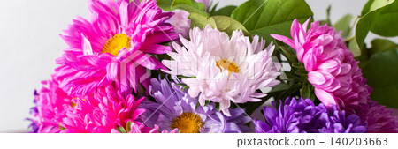 A group of flowers in shades of pink, purple, and white are gathered in a vase. The vase rests on a table. The setting is bright and shows the flowers clearly, banner A group of flowers in shades of pink, purple, and white are gathered in a vase. The vase rests on a table. The setting is bright and shows the flowers clearly, banner 140203663