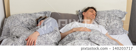 A fifty-year-old couple sleeps side by side in their bedroom at night. They are covered with blankets and resting after a long day, banner A fifty-year-old couple sleeps side by side in their bedroom at night. They are covered with blankets and resting after a long day, banner 140203717