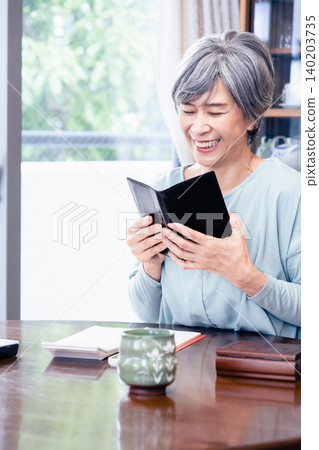 A senior woman holding a notebook. 140203735