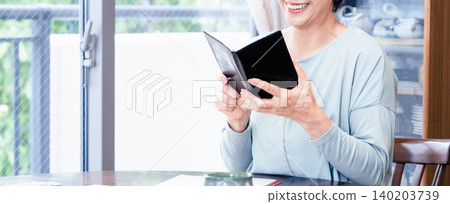 A senior woman holding a notebook. 140203739