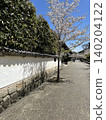 A single road lined with white walls and cherry blossoms. 140204122