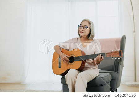Healthy Senior Asian woman musician playing guitar music lover at living room indoors home. Healthy Senior Asian woman musician playing guitar music lover at living room indoors home. 140204150