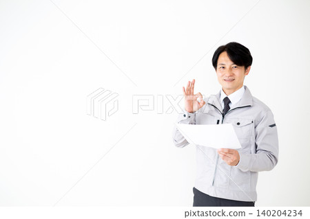 一位身穿灰色工作服的中年商人在白色背景上簽署文件。 140204234