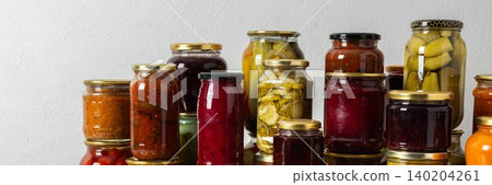 Canning is a common activity in the kitchen as jars filled with vegetables and fruits line the counter. This practice helps in preserving food for winter use and has a long tradition, banner 140204261