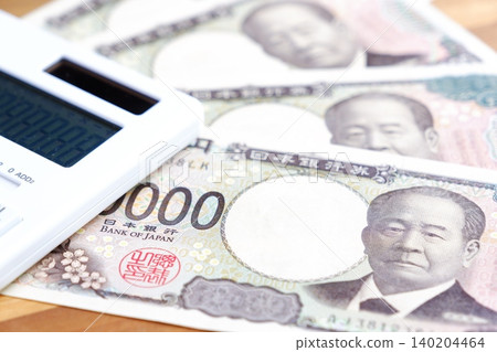 一張10000日元鈔票和一個計算器——一張10000日元鈔票和一個計算器放在桌子上。 一張10000日元鈔票和一個計算器——一張10000日元鈔票和一個計算器放在桌子上。 140204464
