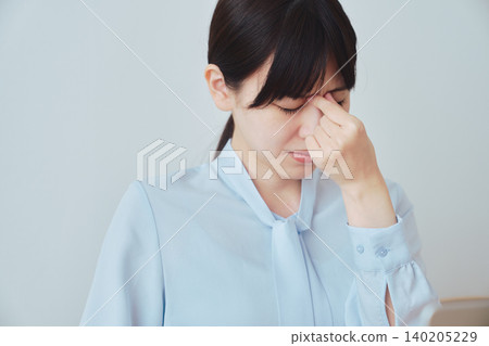 A woman suffering from eye strain due to computer work. A woman suffering from eye strain due to computer work. 140205229