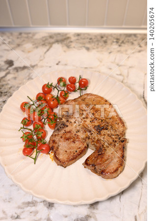 Grilled pork, cherry tomato, white plate, marble counter, home kitchen meal with fresh red vegetable garnish Grilled pork, cherry tomato, white plate, marble counter, home kitchen meal with fresh red vegetable garnish 140205674