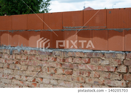 Construction of a house showing contrast between old fired brick foundation and a newly built upper floor from modern brick blocks. Blend of traditional and new building. Construction of a house showing contrast between old fired brick foundation and a newly built upper floor from modern brick blocks. Blend of traditional and new building. 140205703