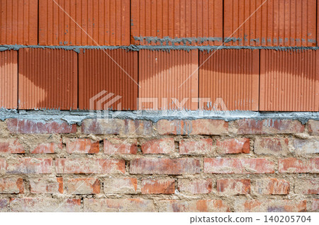 Construction of a house showing contrast between old fired brick foundation and a newly built upper floor from modern brick blocks. Blend of traditional and new building. Construction of a house showing contrast between old fired brick foundation and a newly built upper floor from modern brick blocks. Blend of traditional and new building. 140205704