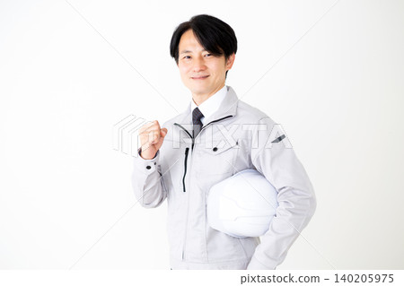身穿灰色工作服的中年商人,手持頭盔,擺出勝利的姿勢,背景為白色。 身穿灰色工作服的中年商人,手持頭盔,擺出勝利的姿勢,背景為白色。 140205975