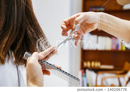 A hairdresser meticulously trims the ends of the hair with a comb and scissors | Salon advertising material A hairdresser meticulously trims the ends of the hair with a comb and scissors | Salon advertising material 140206776