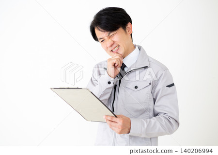 一位身穿灰色工作服的中年商人,在白色背景下,正看著一疊文件,思考著他的工作。 一位身穿灰色工作服的中年商人,在白色背景下,正看著一疊文件,思考著他的工作。 140206994