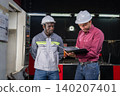 Collaboration between engineers and technicians in industrial setting factory floor documentation review professional environment close-up perspective 140207401