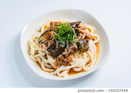 A photo of a chilled udon noodle dish with eggplant and pork, topped with shiso leaves, perfect for summer. 140207449