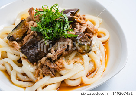 A photo of a chilled udon noodle dish with eggplant and pork, topped with shiso leaves, perfect for summer. A photo of a chilled udon noodle dish with eggplant and pork, topped with shiso leaves, perfect for summer. 140207451