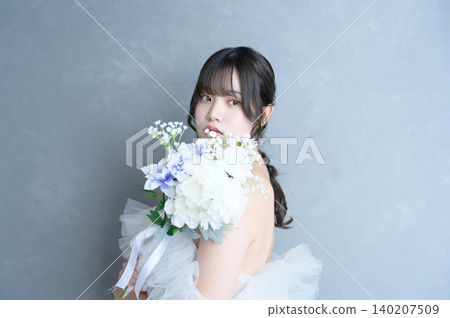 身穿婚紗的日本女子手捧花束,背景是灰色。 身穿婚紗的日本女子手捧花束,背景是灰色。 140207509