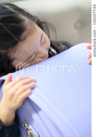 A Japanese girl sleeping on a sofa, hugging her schoolbag. A Japanese girl sleeping on a sofa, hugging her schoolbag. 140207548