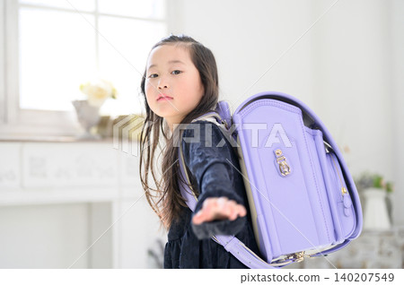 A Japanese girl turns around with her schoolbag on her back. 140207549