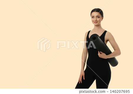 Yoga session with a woman standing and holding a mat 140207695