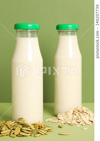Two glass bottles with liquid, seeds, and oats nearby Two glass bottles with liquid, seeds, and oats nearby 140207739